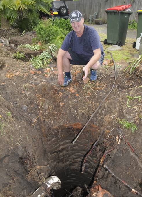 WELL, WELL, WELL: Russell Street resident Phillip Watkins with the well found on his boundary during excavation to replace the fence. Photo: CHRIS SEABROOK 112316cwell1