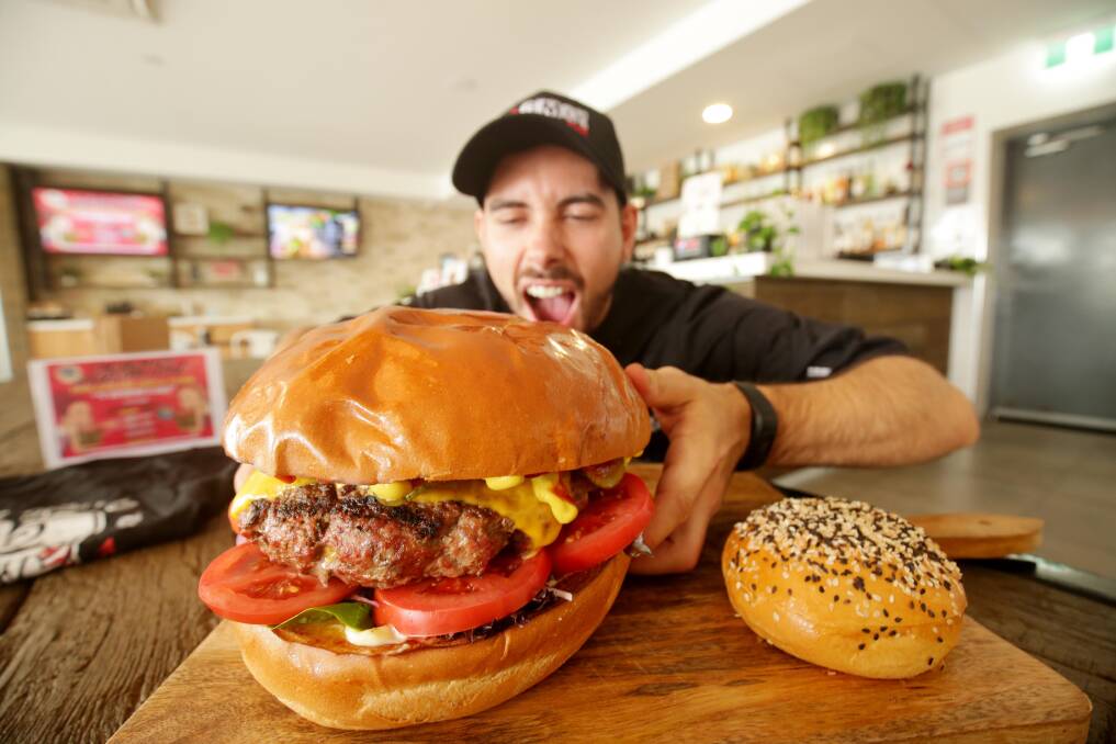OMC staff member Taylor Krmac attempting to take a bite out of the two kilogram Big Mouth Burger. Picture: Chris Lane 