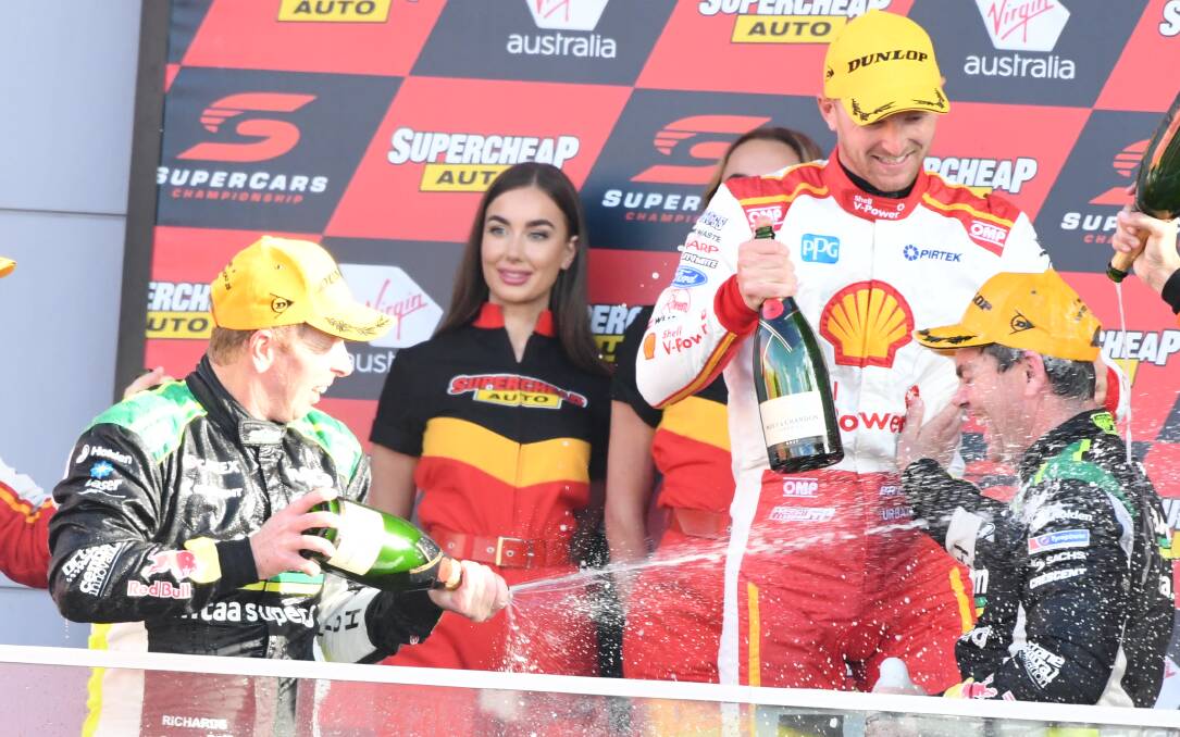 TAKE THAT: Steven Richards gives Craig Lowndes a spray of champagne. Photo: CHRIS SEABROOK
