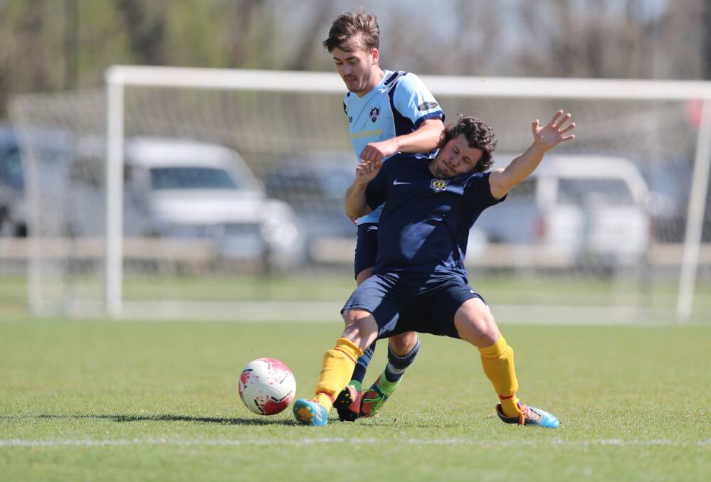 BATTLING IT OUT: Collegians FC's Myles Russell and Abercrombie FC Gold's Nick Ioannides fight for possession. Photo: PHIL BLATCH
