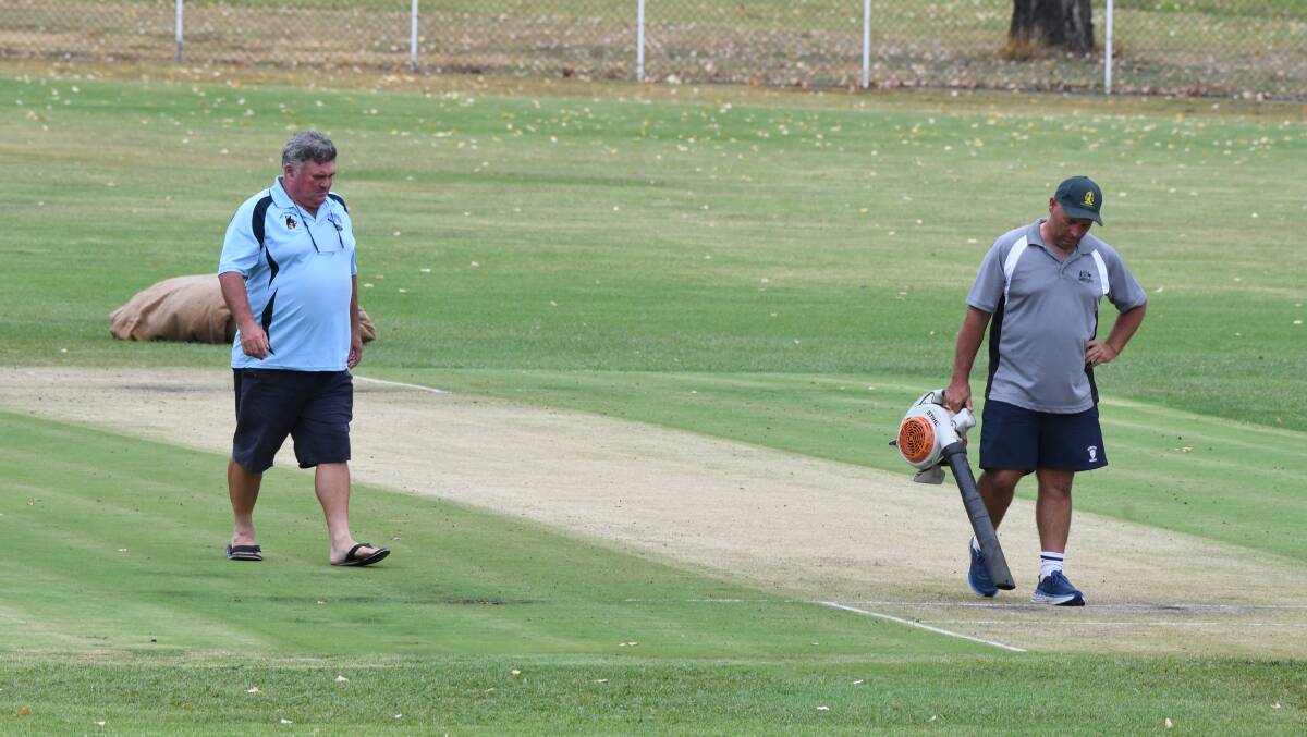 BREAK IN THE WEATHER: President of Blue Mountains Cricket Ian Strudwick inspects the pitch on Sunday as Bathurst District Cricket Association vice-president Shane Broes helps dry the wicket. Photo: CHRIS SEABROOK 022518cscots1