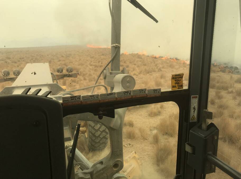 In his grader, cutting a containment line as the firefront approaches. Picture: Robbie Wallace