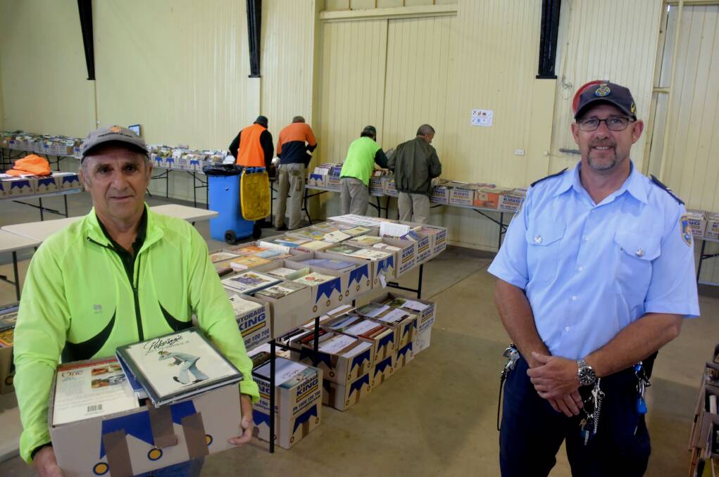 PARTNERSHIP: Lifeline's Book fair coordinator Bill Miller and senior overseer of Community Projects, Scott Keen, with inmates working in the background. Photo: RACHEL CHAMBERLAIN 101818rcbooks