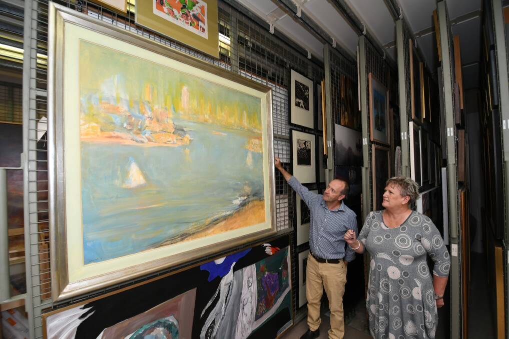 GOOD RESULT: Collections manager Tim Pike with councillor Jacqui Rudge, looking at a Lloyd Rees painting that is in storage. Both are thrilled that a purpose-built collections facility will go ahead. Photo: CHRIS SEABROOK 013019collectn2
