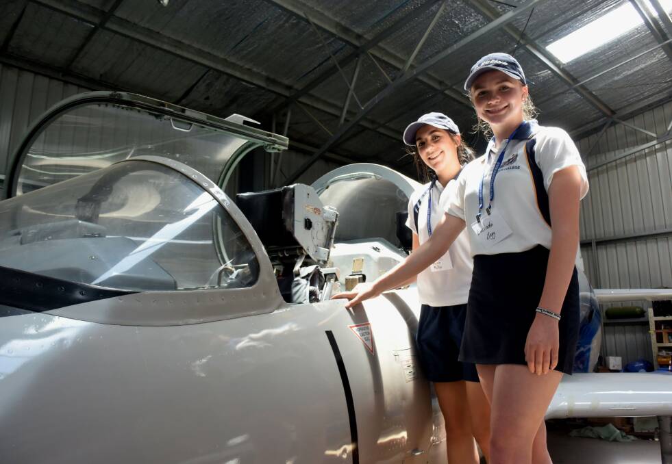LEARNING EXPERIENCE: Year 12 students Taylah Muller and Lucinda Begg beside one of the aircraft they got to see during the hangar tour on Friday. Photo: RACHEL CHAMBERLAIN 112919rcfly1