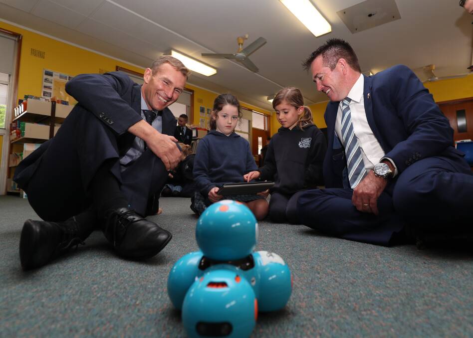 SCHOOLED: Minister for Education Rob Stokes and member for Bathurst Paul Toole, getting a robotics lesson from Year 1 students Emily O'Leary and Poppy Shoemark at Bathurst South Public School. Photo: PHIL BLATCH 112818pbrobot3