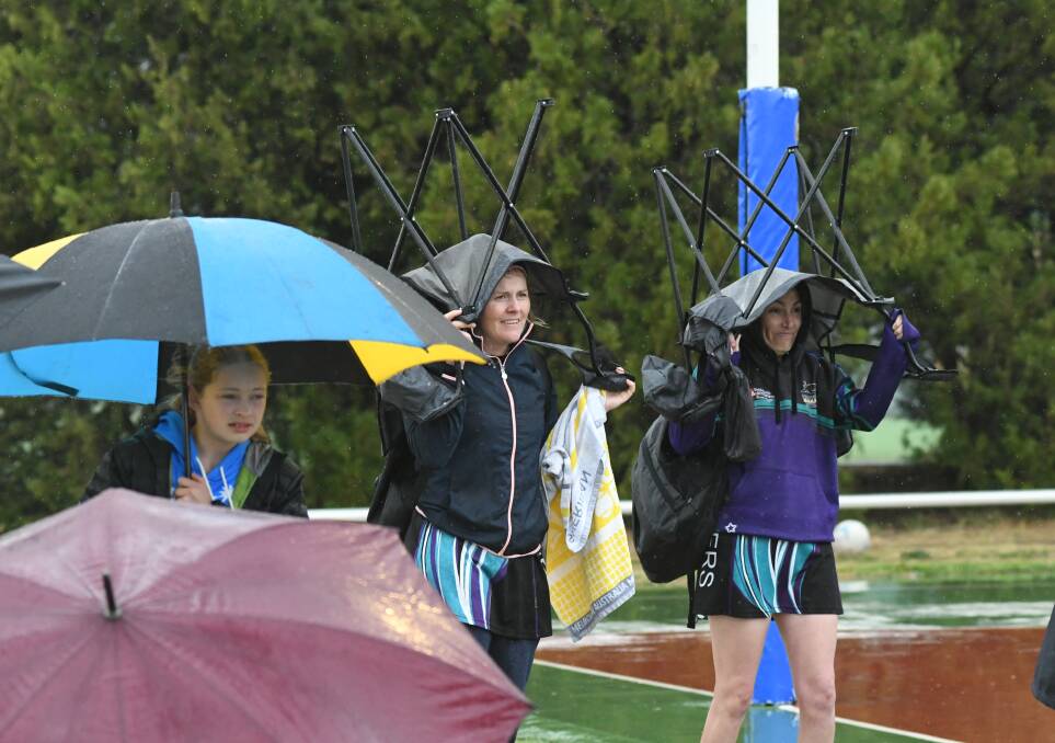 SNAPSHOT: These ladies used fold up chairs in an effort to escape the heavy rain on Saturday. Photo: CHRIS SEABROOK 092119cnetbgf13