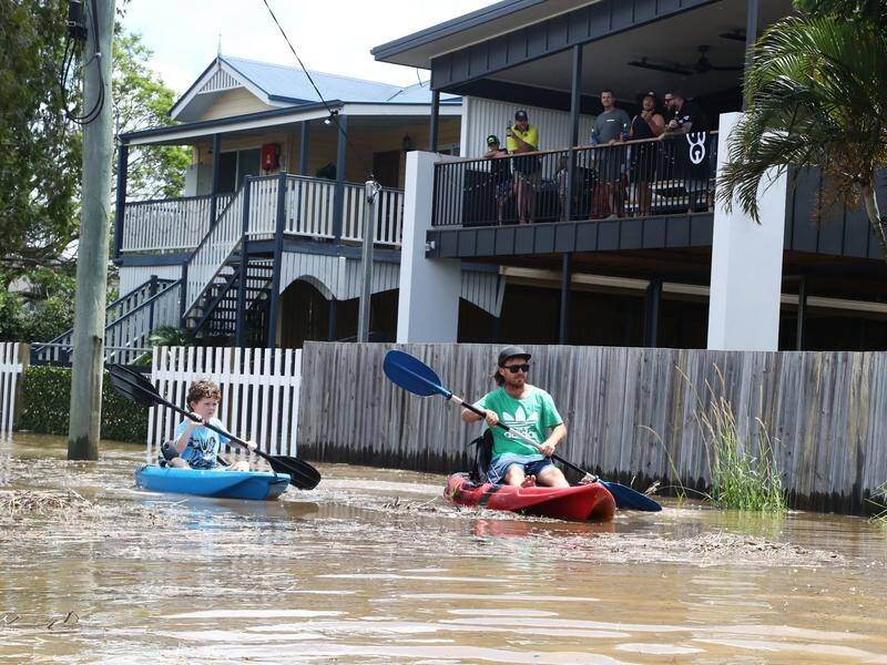 Residents paddle kayaks down a street in Tumbulgum in northern NSW during flooding.