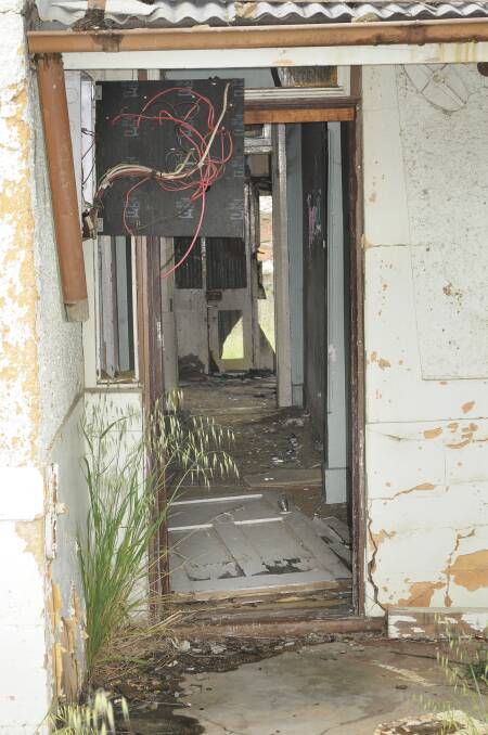 A REAL MESS: The door of this William Street house has been kicked in, broken glass and needles litter the floor and the wiring has been left exposed. Photo: CHRIS SEABROOK 101314cdump2