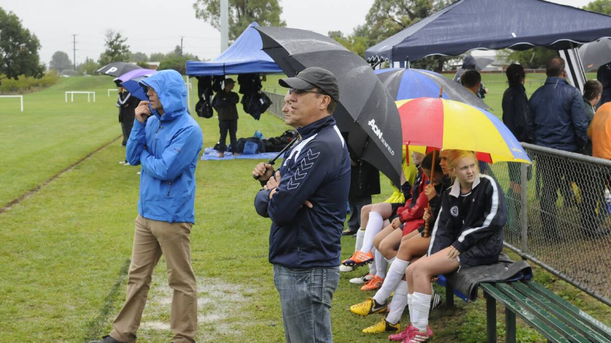 WET WELCOME FOR VISITORS: Parents and players took to umbrellas and makeshift tents to try and stay dry during the Proctor Park Challenge. Parts of the car park resembled a ploughed field. Photo: CHRIS SEABROOK 030114csocg2