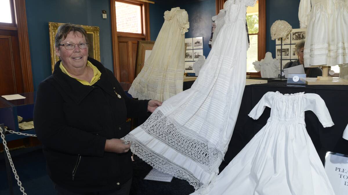 BEAUTIFUL WORK: The Bathurst and District Historical Society’s Judy Attard with the Edwards’ family’s beautiful 1863 christening gown, an important part of the exhibition. 	051116pgowns