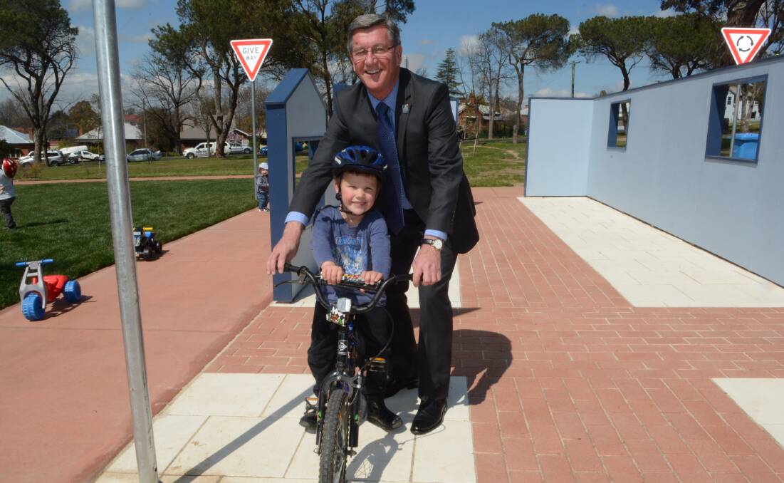 SAFE AND FUN: Young Bathurst resident James Lloyd showed mayor Gary Rush a thing or two about riding a bike at the new bike education track at the Adventure Playground.
Photo: PHILL MURRAY	 091015padventure