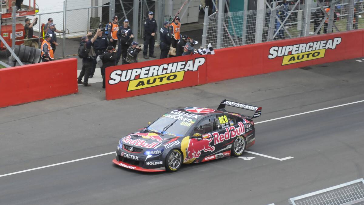 SIX OF THE BEST: Craig Lowndes brings the Triple Eight Racing Commodore past the chequered flag for his sixth career win in the Bathurst 1000, and the fourth for his co-driver Steven Richards. Photo: CHRIS SEABROOK 	101115cfinish1a