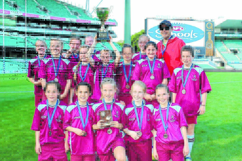 CHAMPIONS: The Holy Family School girls Australian rules team and their coach Joe Pucci show off the Paul Kelly Cup they won at the SCG on Monday. 	IMG_2889