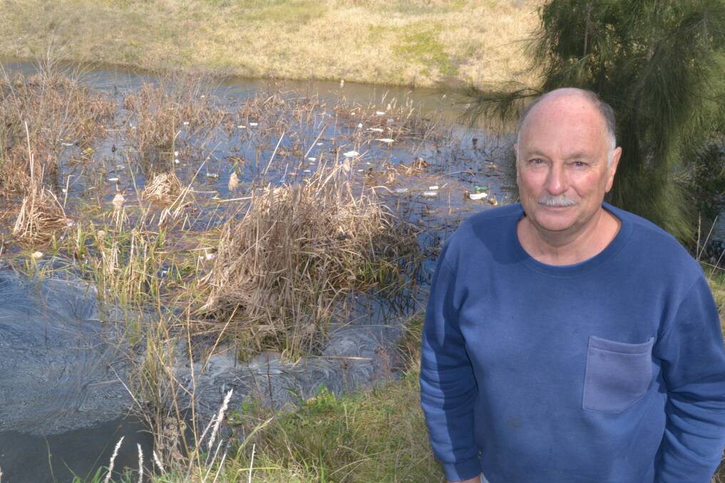 CESSPIT: Jim Schaerf stands in front of the holding pond at the top of Hector Park, which is full of litter and pollution. Photo: BRIAN WOOD 081214bwlitter