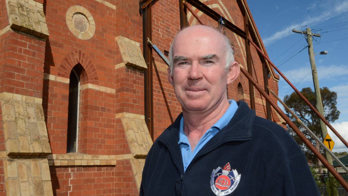 AT EASE: Former firefighter Graham Gibbons has called it a day after serving the community for the last 35 years. He is pictured outside the St Barnabas’ Anglican Church which was destroyed by fire in February, 2014. Photo: PHILL MURRAY 050115pgraeme