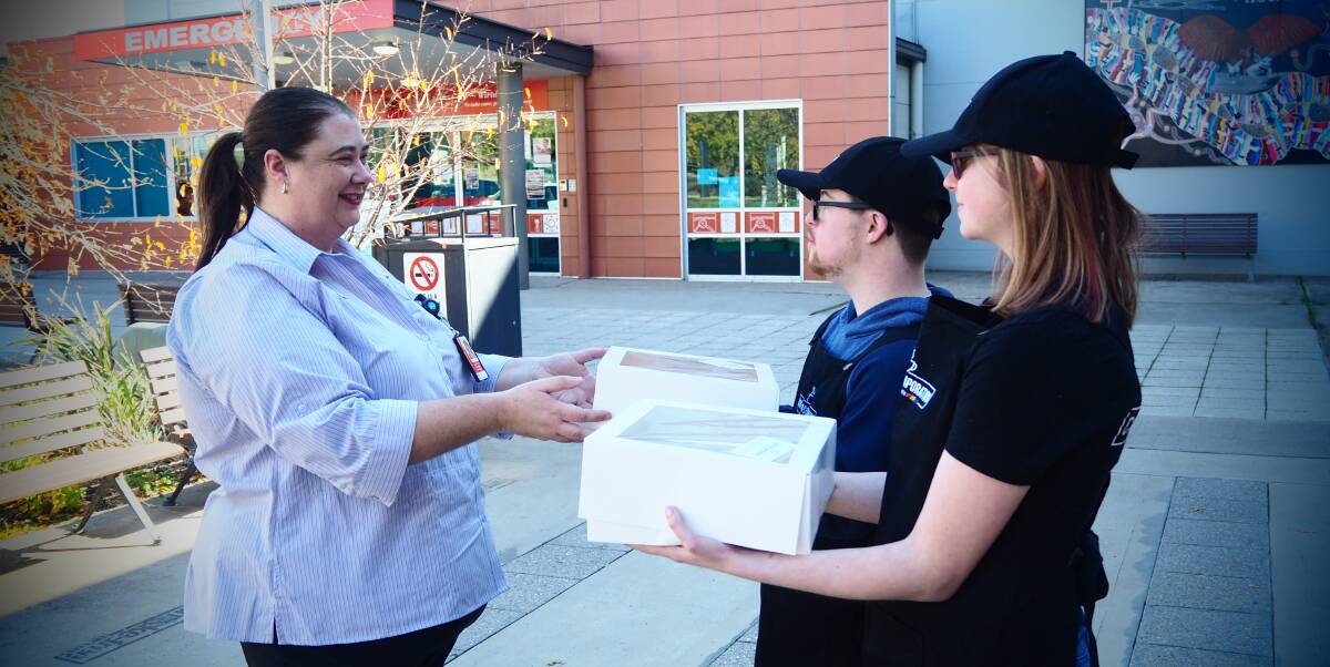 KIND GESTURE: Bathurst Hospital medical records staff member Leanne Hunter-Knight accepts a catering order from Cafe on Corporation's Mitchell Smith and Lara Matheson. Photo: SAM BOLT