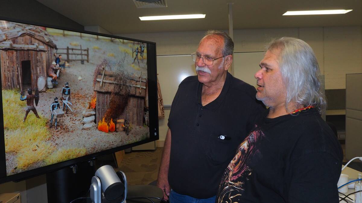 FILLING THE GAPS: Wiradyuri elders Mallyan [Uncle Brian Grant] and Dinawan Dyirribang [Uncle Bill Allen] with an image of a diorama documenting the 1824 Bathurst Wars in a new exhibition at Sydney's Hyde Park Barracks.