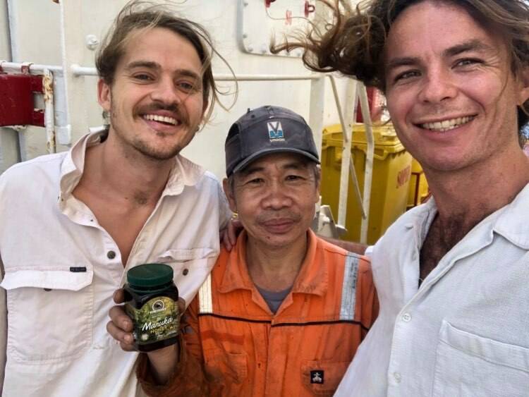 GRAVE CONCERNS: William Mainprize [right] and friend Harry Morrison presenting a jar of Manuka honey to a fellow crew member in July. Photo: SUPPLIED