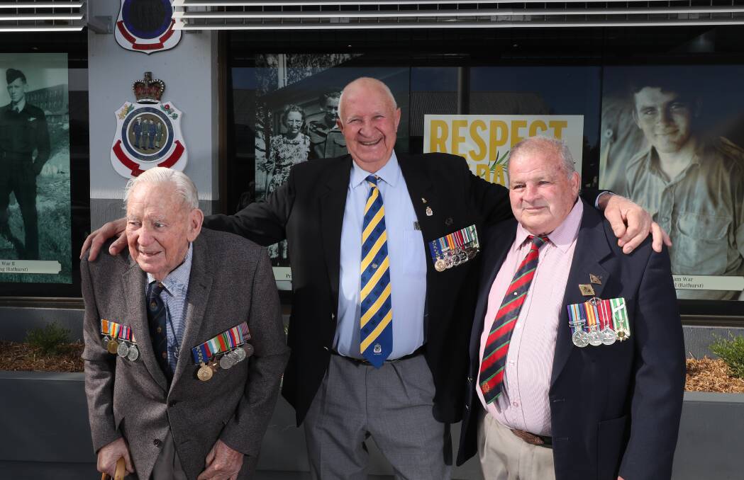 RESPECT THE DAY: War veterans Dick Crossing, Brian Tobin and Lyle Orreal pose in front of their portraits outside the Bathurst RSL Club. Photo: PHIL BLATCH 042219pbrsl1
