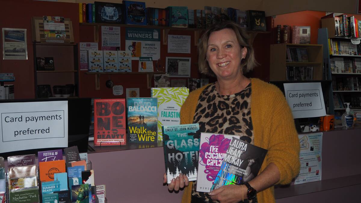 BOOK IT IN: BooksPlus staff member Mel Gumpert with some popular new releases on sale at the store.