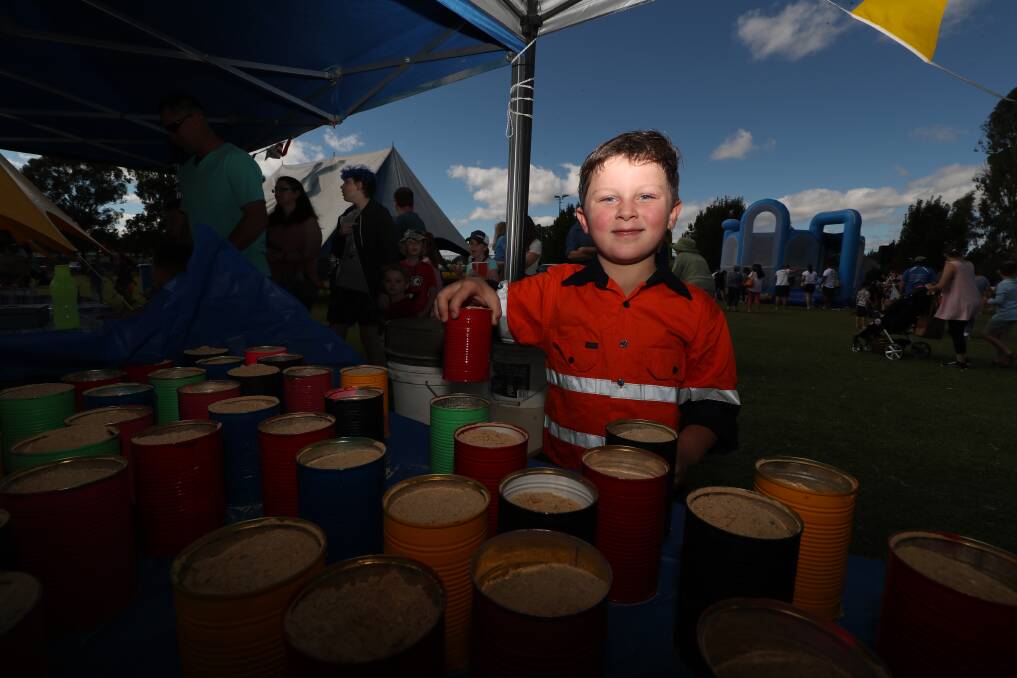 COLOURFUL CANS: Tomasi Tate tries his hand at an attraction at the Eglinton Country Fair on Saturday. Photo: PHIL BLATCH 022319pbeg5