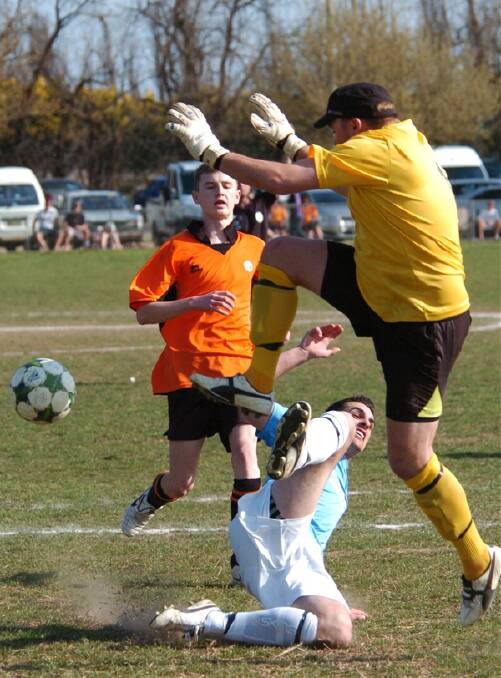 SO CLOSE: Kirby Earle from City Colts makes a desperate lunge for the ball while Macquarie United goalkeeper Evan Deveney tries to clear the ball during Sunday’s thrilling first grade decider at Proctor Park. Photo: ZENIO LAPKA 091811zsoccer6