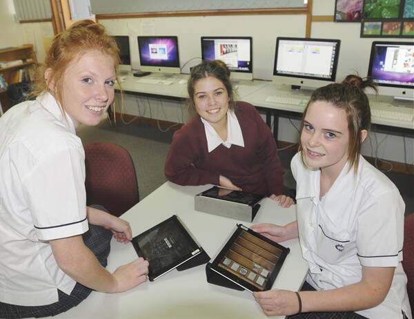 NEW TECHNOLOGY: MacKillop College Year 11 students Anna Fenlon, Kirilly Whitney and Tash Ryan with their iPads in class this week. Photo: CHRIS SEABROOK 	030512cipads2