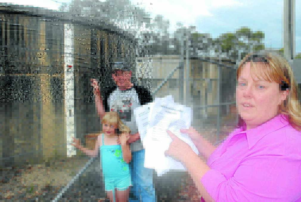 A LONG, DRY SUMMER: Leonie MacBeth with letters sent to her by Bathurst Regional Council. Her husband, David, and daughter, Maddy, 7, are alongside the reservoir that holds water pumped from the bore on Hillview Estate at Walang. Photo: CHRIS SEABROOK 112812cutoff