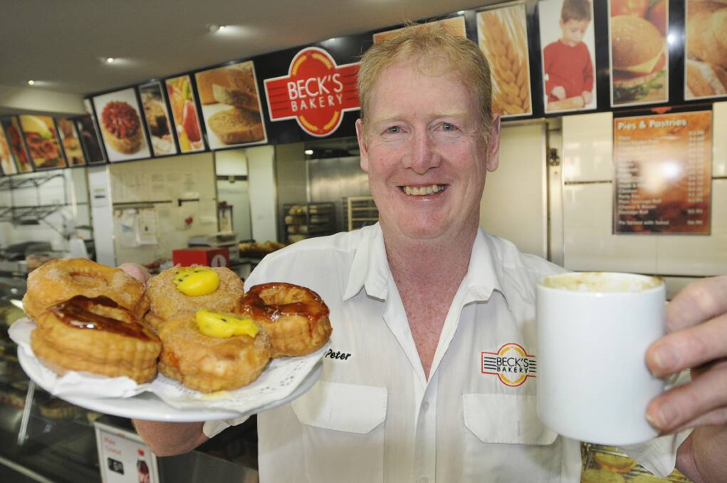 FLYING OFF THE SHELF: Baker Peter Neubeck with a sample of some of the varieties of cronuts available at Beck’s Bakery. Photo: CHRIS SEABROOK 081313cronuts